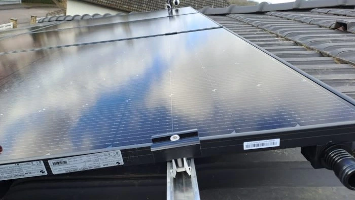 Rail de montage et pince de serrage entre deux capteurs solaires sur une toiture inclinée